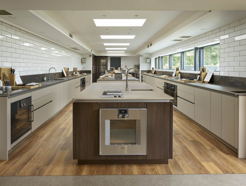 Contemporary kitchen showing run of kitchen units and island finished with porcelain worktops and built in Gaggenau appliances