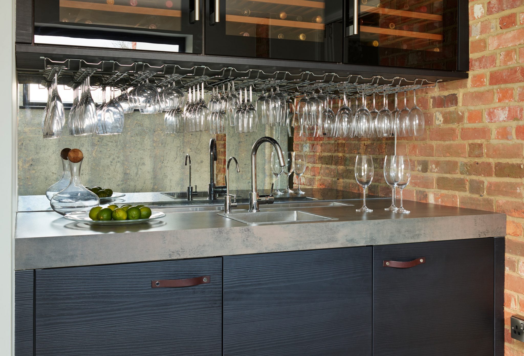 Three over-counter wine cooler units above bar area with grey composite marble counter-top and dark navy base units with leather handles