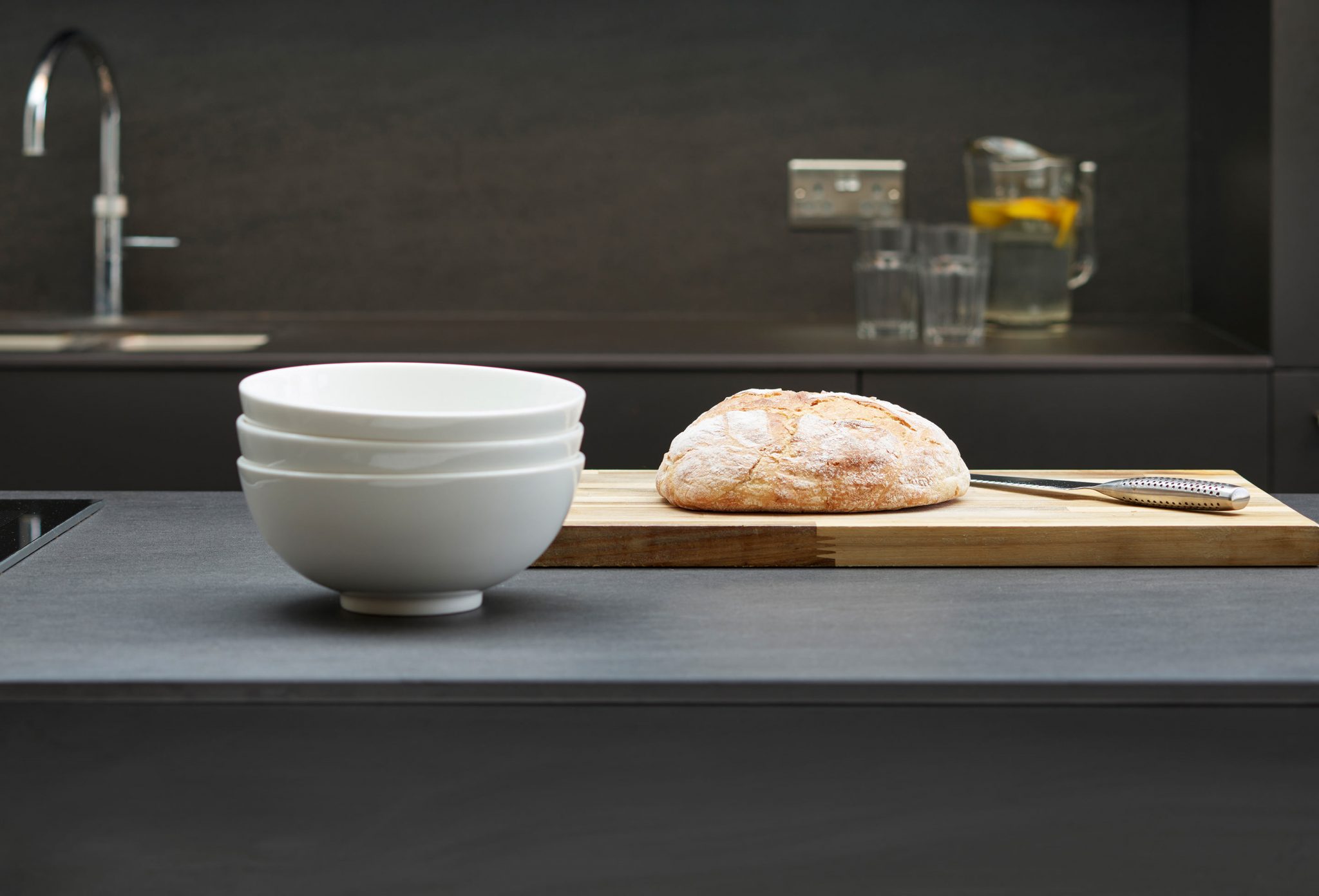 Modern, contemporary kitchen, with dark porcelain worktop with choppping board and loaf of bread
